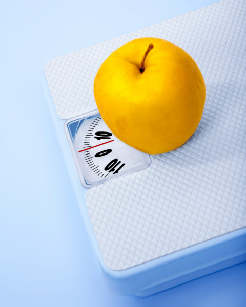 Apple on scale, body weight watching, conceptual image of dieting, calorie count, healthy lifestyle and shape control