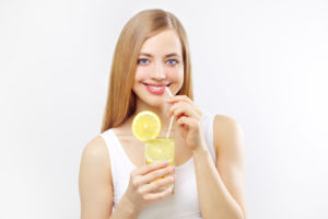 Девушка пьет воду с лимонным соком